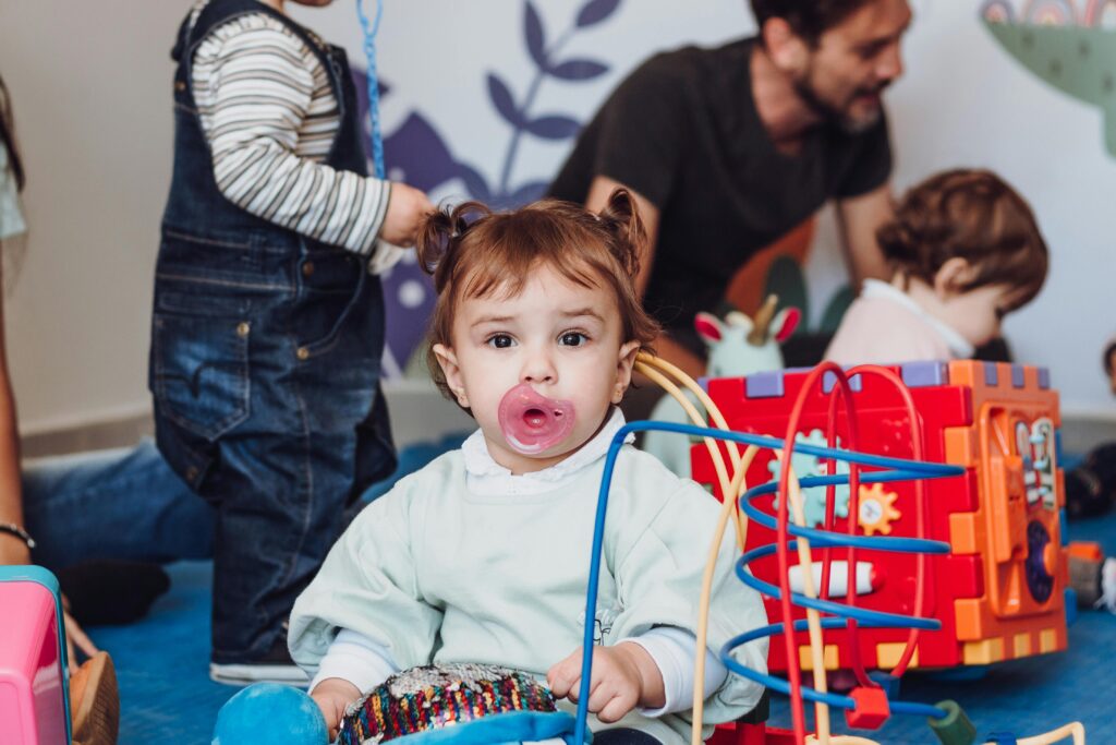 Cute young child with pacifier playing in a colorful indoor playroom setting.
