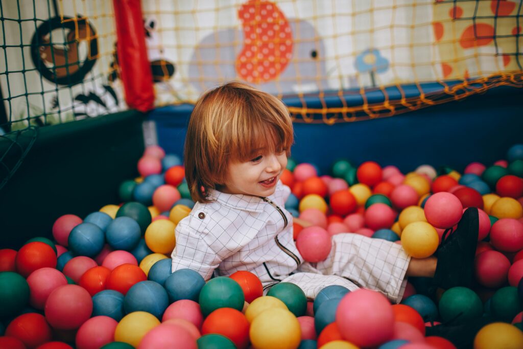 A cheerful child enjoying playtime in a colorful indoor ball pit.